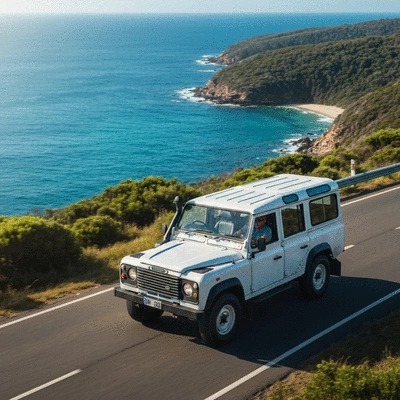 Well-maintained white vintage 4x4 SUV driving on a scenic coastal road